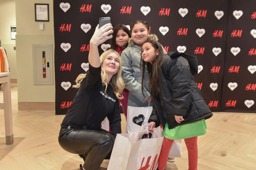 Children pose for a selfie with an H&M staff member after completing a shopping spree at an event between H&M and the charity GLAM4GOOD to provide a shopping and styling experience to disadvantaged youth in the Detroit area at the H&M Downtown Detroit store on Dec. 16, 2019. (Aaron J. Thornton/Getty Images for H&M)