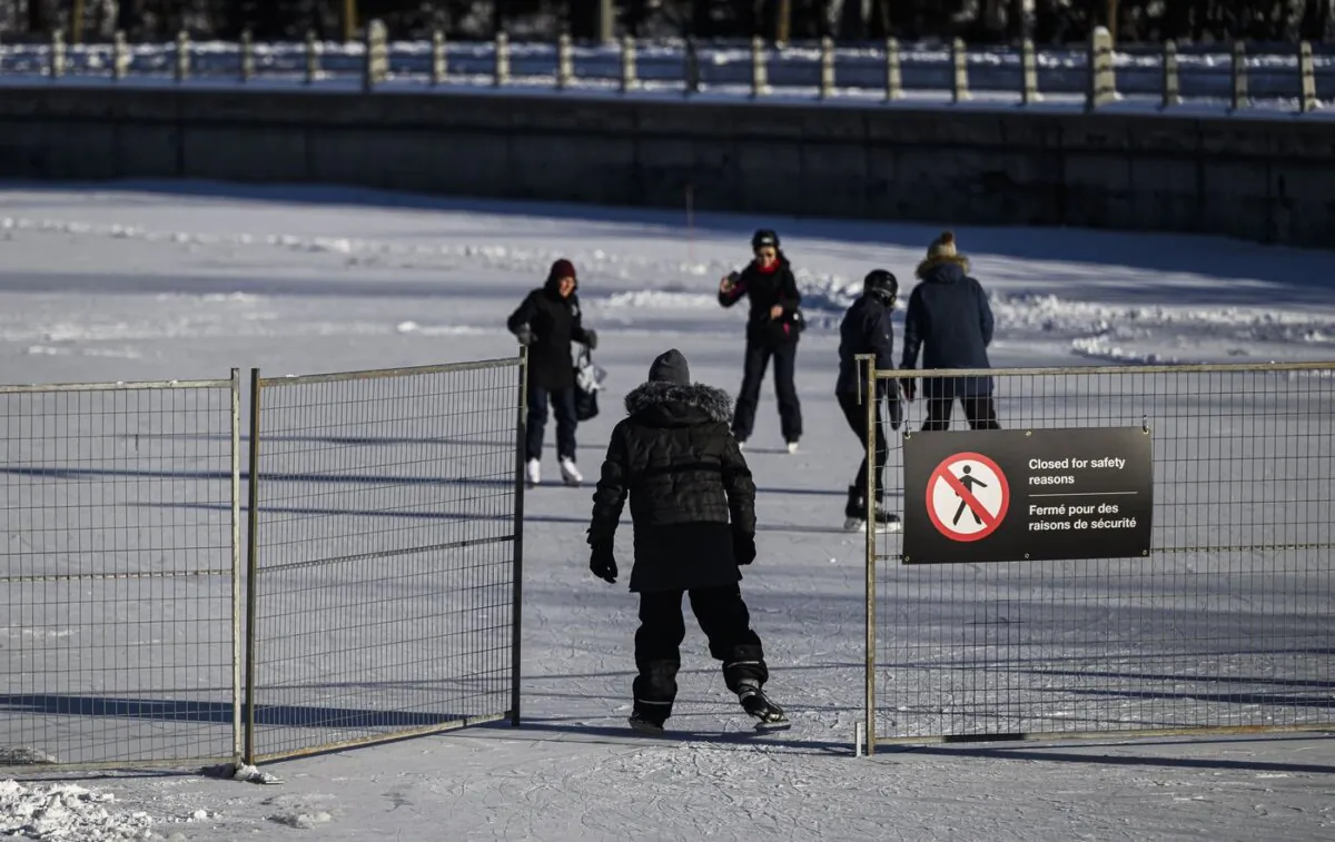 People skate past an opening in a fence at a closed section of the Rideau Canal Skateway, on the morning of its opening day in Ottawa, on Jan. 21, 2024. (The Canadian Press/Justin Tang)
