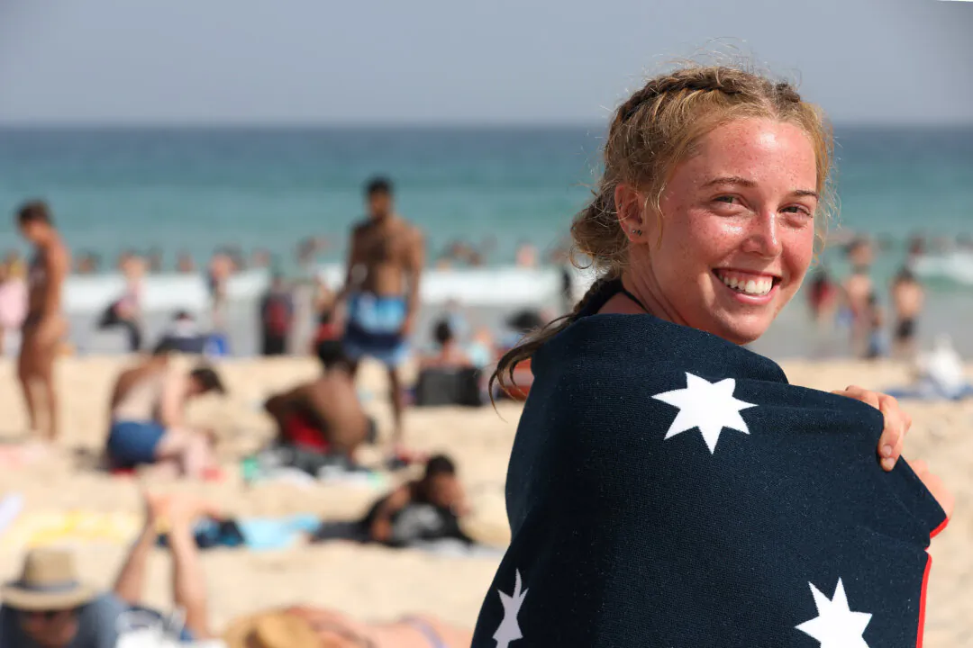 A girl wrapped in an Australian flag towel smiles into the camera as thousands flock to Bondi Beach to beat the scorching heat during Australia Day in Sydney, on Jan. 26, 2019. (Cole Bennetts/Getty Images)