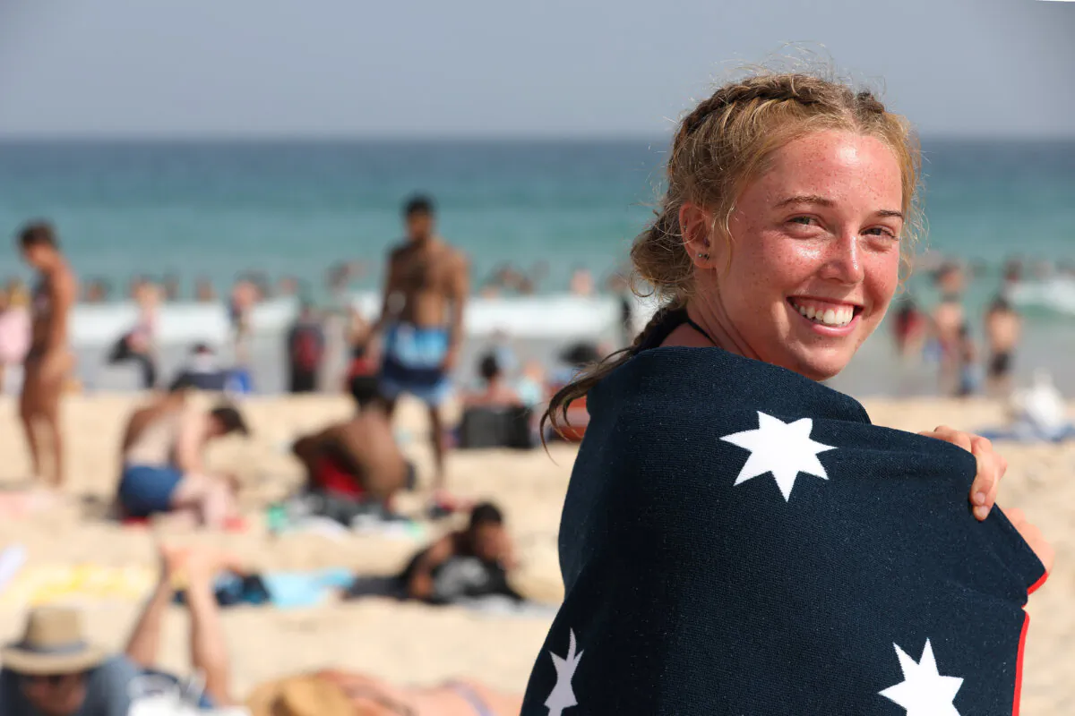 A girl wrapped in an Australian flag towel smiles into the camera as thousands flock to Bondi Beach to beat the scorching heat during Australia Day in Sydney, on Jan. 26, 2019. (Cole Bennetts/Getty Images)