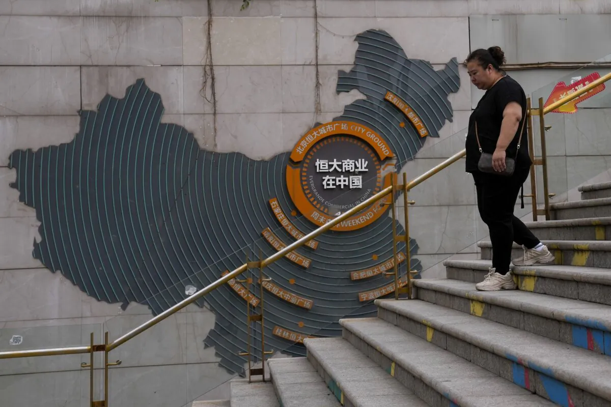 A woman walks by a map showing Evergrande development projects in China as she heads to an Evergrande city plaza in Beijing on Sept. 18, 2023. (Andy Wong/AP Photo)