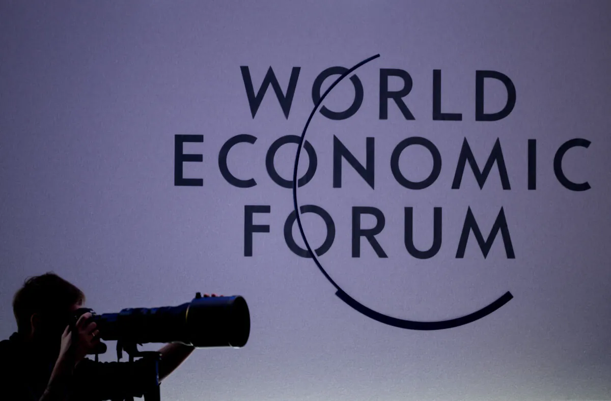 A press photographer works next to the logo of the World Economic Forum (WEF) at the opening of their annual meeting in Davos on Jan. 15, 2024. (Fabrice Coffrini/AFP via Getty Images)
