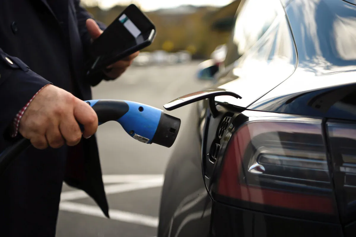 A customer prepares to charge his Tesla electric vehicle after parking in a bay for electric vehicles at a supermarket in north London on Nov. 18, 2020. (Daniel Leal-Olivas/AFP via Getty Images)