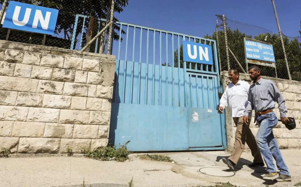 Palestinians pass by the gate of an UNRWA-run school in Nablus in the West Bank, Aug. 13, 2018. (Abed Omar Qusini/Reuters)