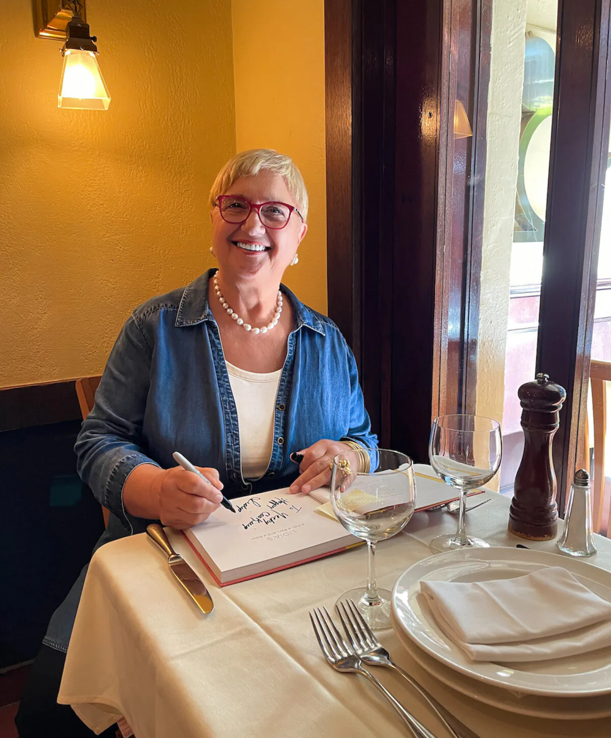 Chef Lidia Bastianich autographs one of her books at a table in Becco. (Erika Heymann/WGBH/PBS/TNS)