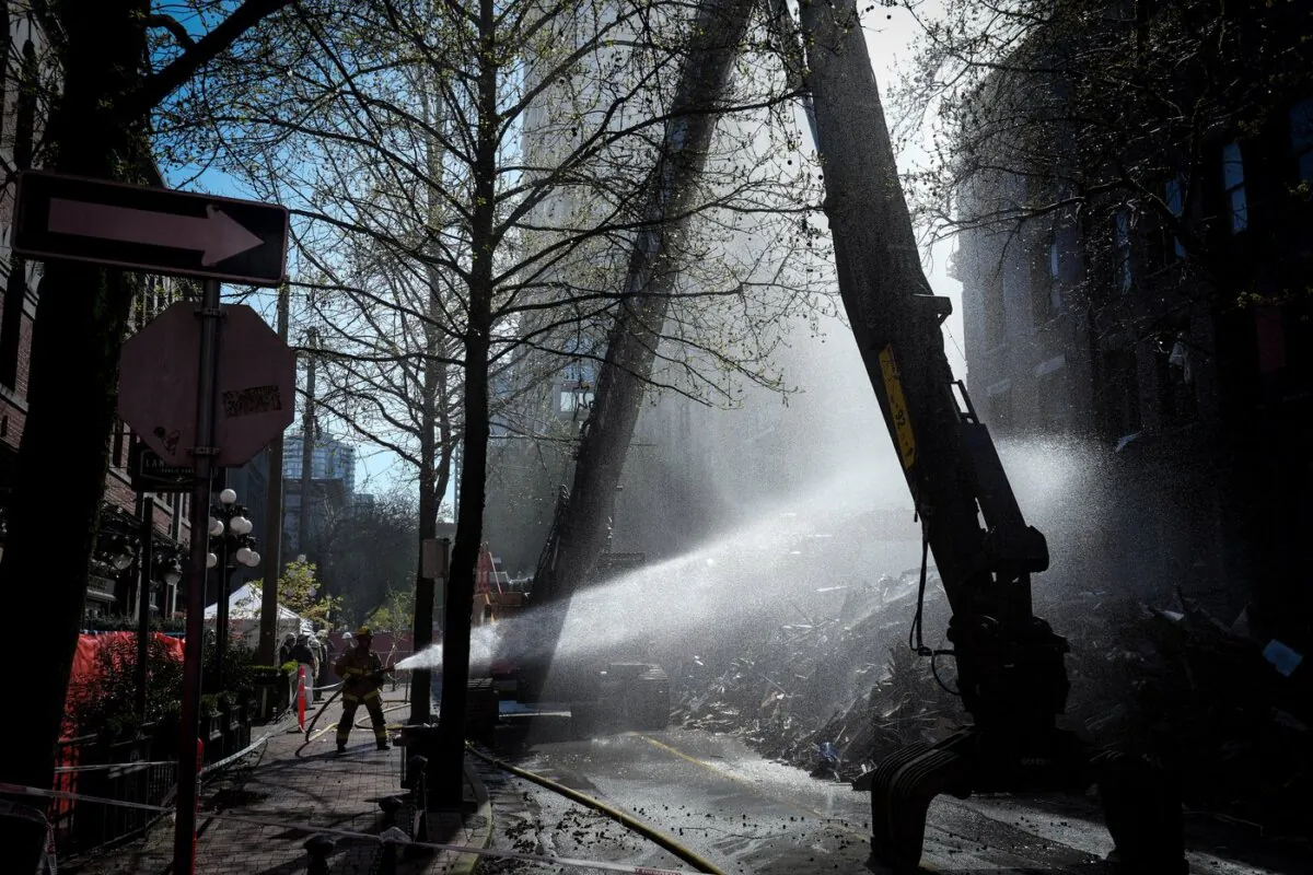 A firefighter sprays water on debris during demolition of the Winters Hotel in Vancouver, B.C., on April 22, 2022. (The Canadian Press/Darryl Dyck)