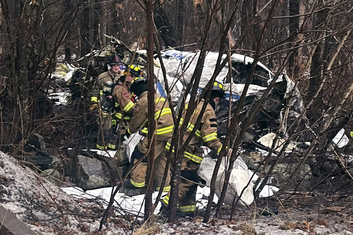 Firefighters recover items from the site of a small plane crash at rear in a wooded area behind his home in Londonderry, N.H., on Jan. 26, 2024. (Eddie Saktanaset photo via AP)
