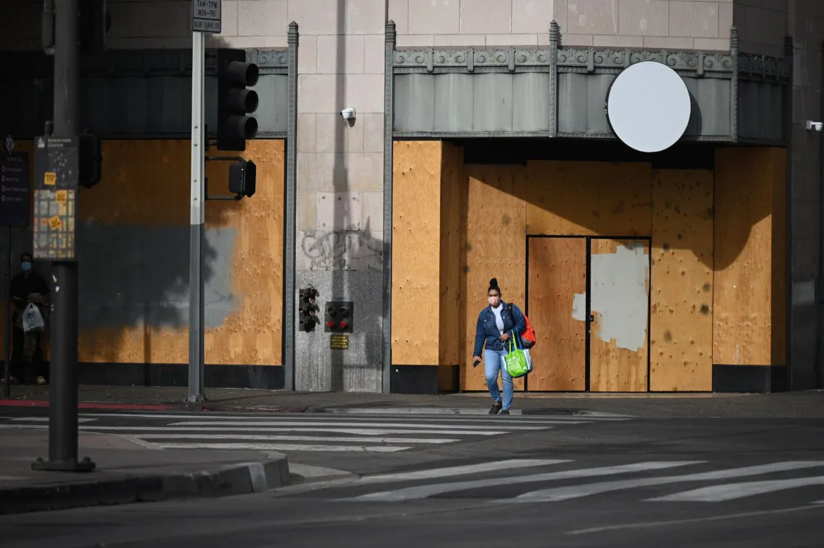 A woman walks past a boarded up business in a file photo. (Robyn Beck/AFP via Getty Images)