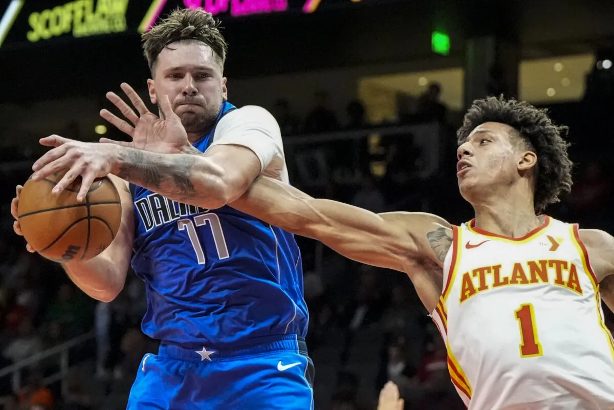 Dallas Mavericks guard Luka Doncic (77) grabs a rebopund from Atlanta Hawks forward Jalen Johnson (1) during the first half of an NBA basketball game in Atlanta on Jan. 26, 2024. (Mike Stewart/AP Photo)