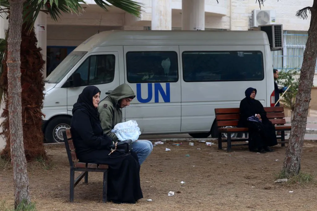 Displaced Gaza residents sit on benches as they wait outside a clinic of the United Nations Relief and Works Agency for Palestine Refugees (UNRWA) in Rafah in the southern Gaza Strip on Jan. 28, 2024. (AFP via Getty Images)