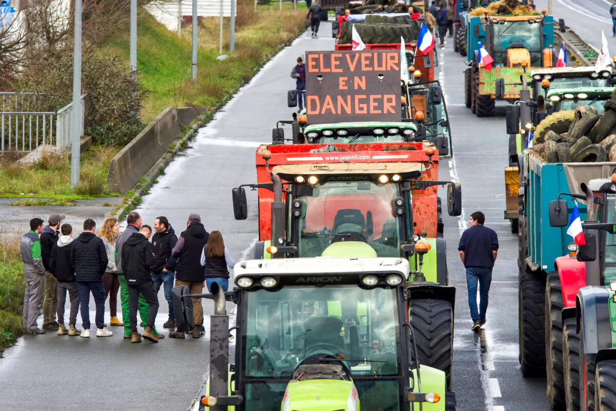 French farmers stop their tractors on the D338 road in Le Mans, northwestern France, on Jan. 26, 2024 as part of a nationwide day of protests called by several farmers unions on pay, tax, and overregulation. The sign on one of the tractors reads "éleveur en danger" meaning "breeder in danger." Farmers have fumed at what they say is a squeeze on purchase prices for produce by supermarket and industrial buyers, as well as complex environmental regulations. (GUILLAUME SOUVANT/AFP)