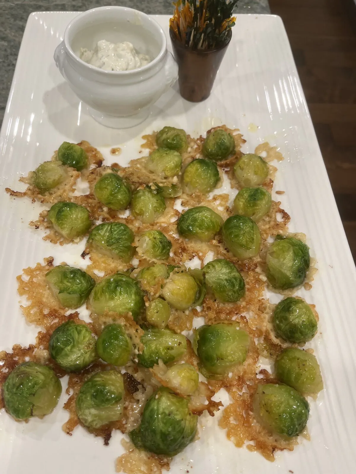 Small Brussels sprouts are trimmed, halved and arranged on top of shredded Parmesan rounds on parchment paper. (Diane Rossen Worthington/TNS)
