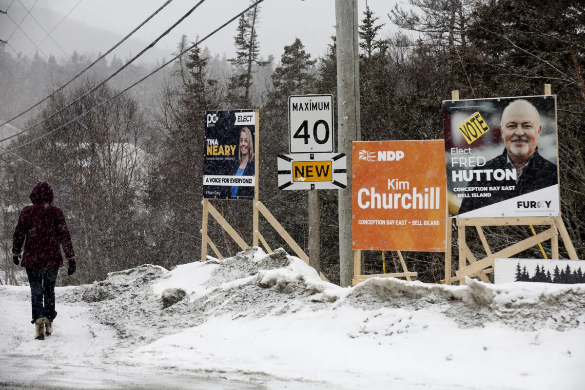 A person walks past campaign signs for the provincial byelection for the riding of Conception Bay East-Bell Island, N.L., on Jan.29, 2024. (The Canadian Press/Paul Daly)