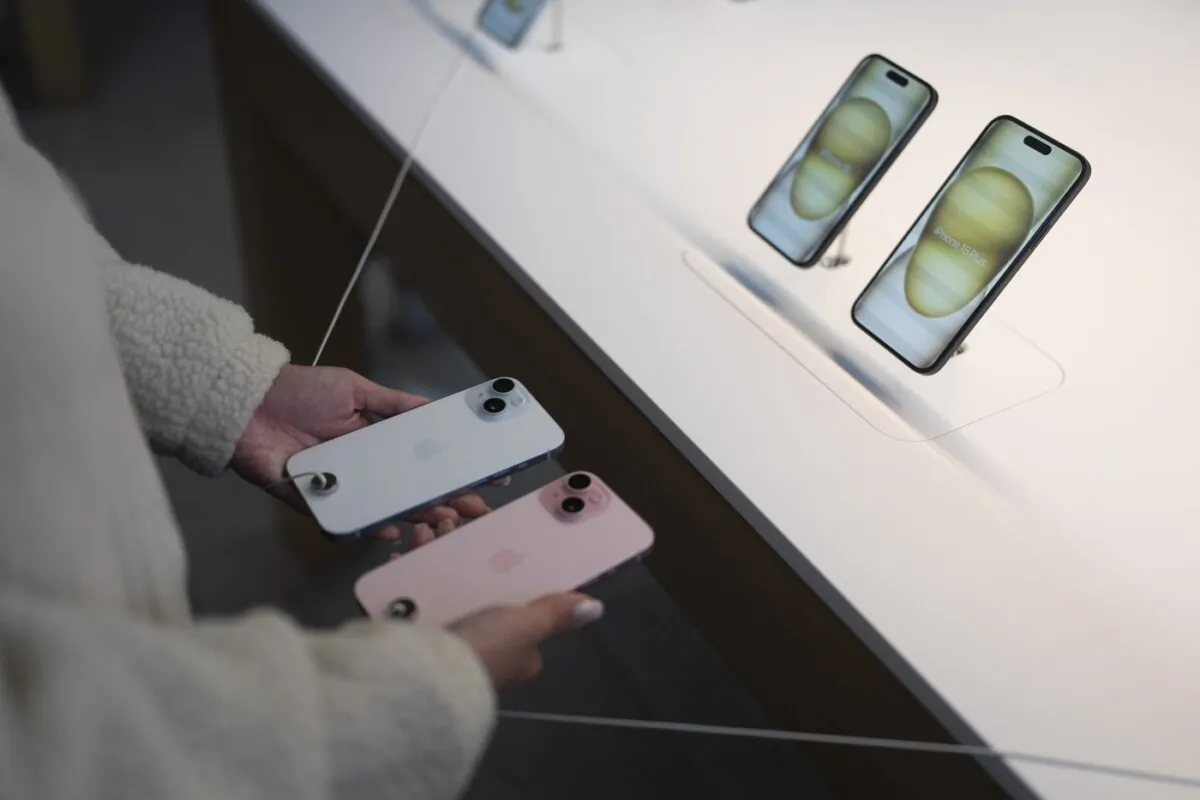 A shopper compares two iPhone 15 models on the first day of sales at an Apple Store in Los Angeles, Sept. 22, 2023. (The Canadian Press/AP-Jae C. Hong)