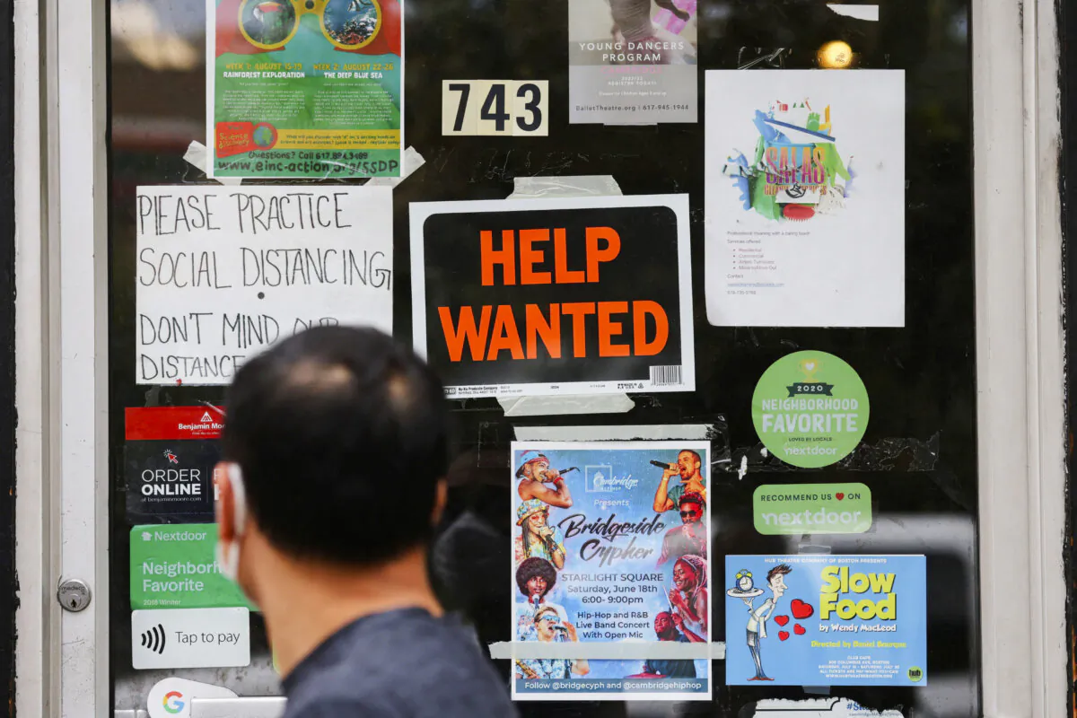 FILE PHOTO: A pedestrian passes a "Help Wanted" sign in the door of a hardware store in Cambridge, Massachusetts, U.S., July 8, 2022. REUTERS/Brian Snyder