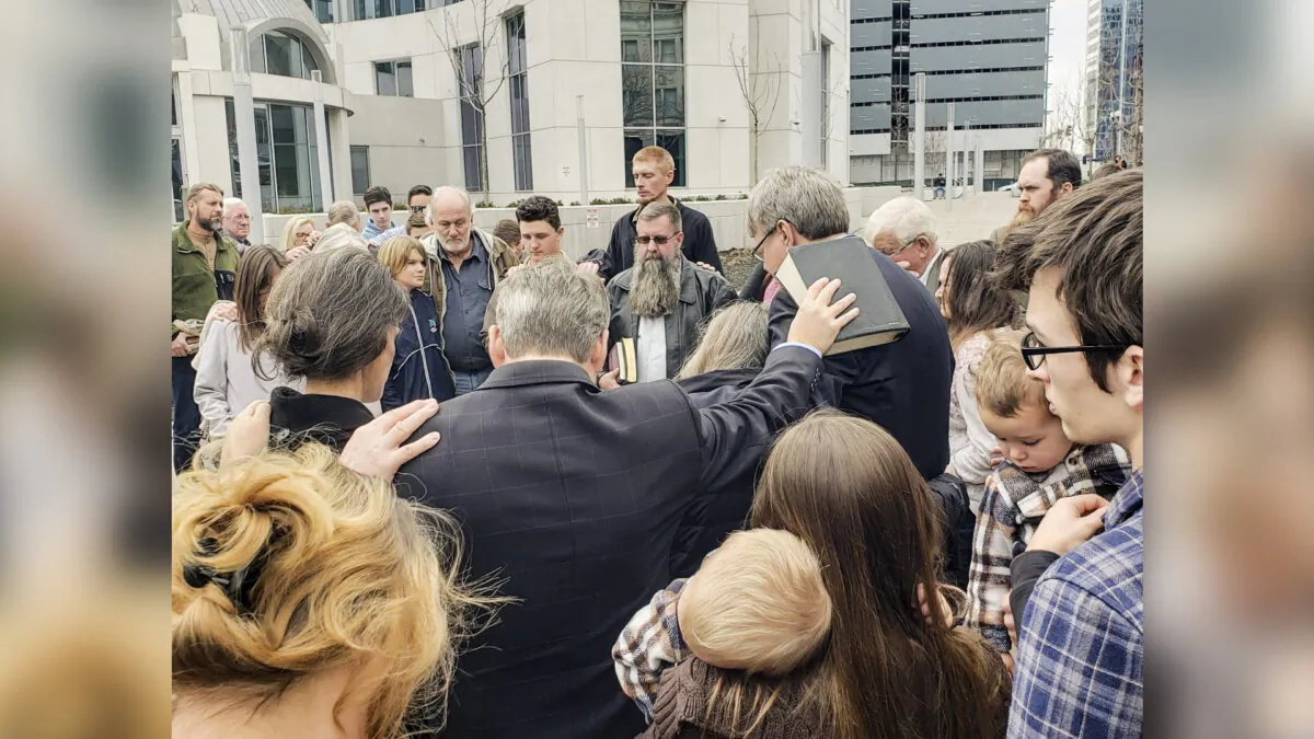 Pro-life advocate Paul Vaughn (C) holds a Bible on Cal Zastrow's back as they stand with others outside the Fred D. Thompson U.S. Courthouse and Federal Building in Nashville, Tenn., minutes after they were found guilty of violating the federal FACE Act, on Jan. 29, 2023. (Courtesy of Amanda Place)