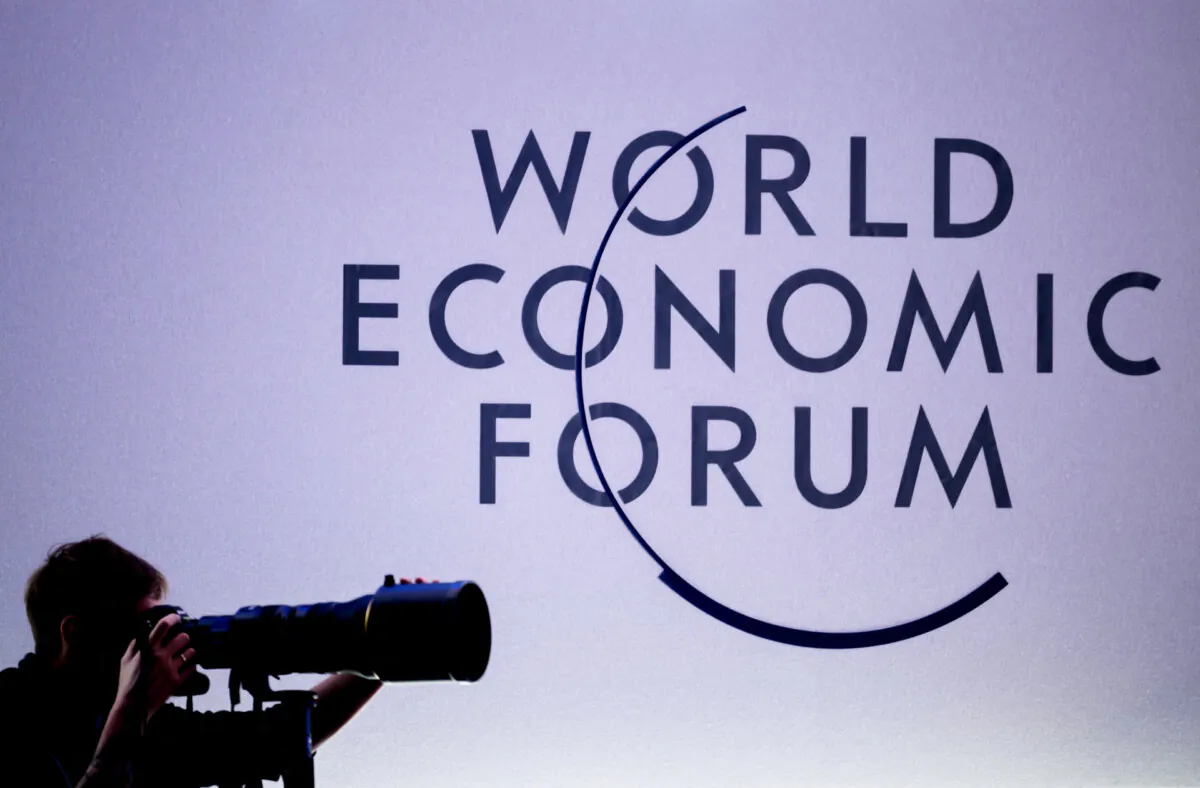 A press photographer works next to the logo of the World Economic Forum (WEF) at the opening of the annual meeting in Davos on Jan. 15, 2024. (Fabrice Coffrini/AFP via Getty Images)