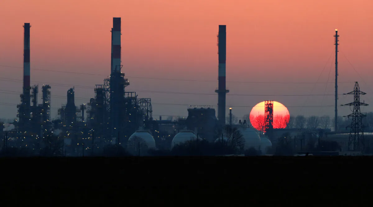 The sun sets behind the chimneys of the Total Grandpuits oil refinery, southeast of Paris, France, on March 1, 2021. (Christian Hartmann/Reuters)