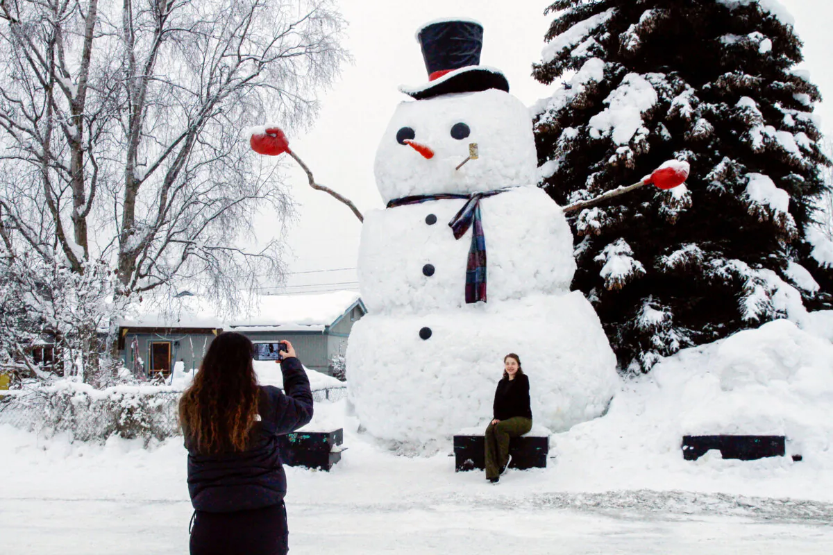 Isil Mico takes a photo of her sister-in-law Oznur Mico in front of Snowzilla, a snowman measuring more than 20 feet tall, in Anchorage, Alaska on Jan. 10, 2024. (Mark Thiessen/AP Photo)