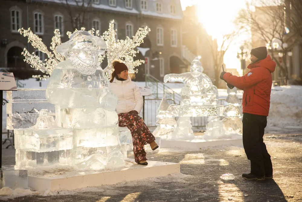 A couple takes photos near the ice sculptures at the Carnaval de Quebec. (Photo courtesy of Audet Photo)