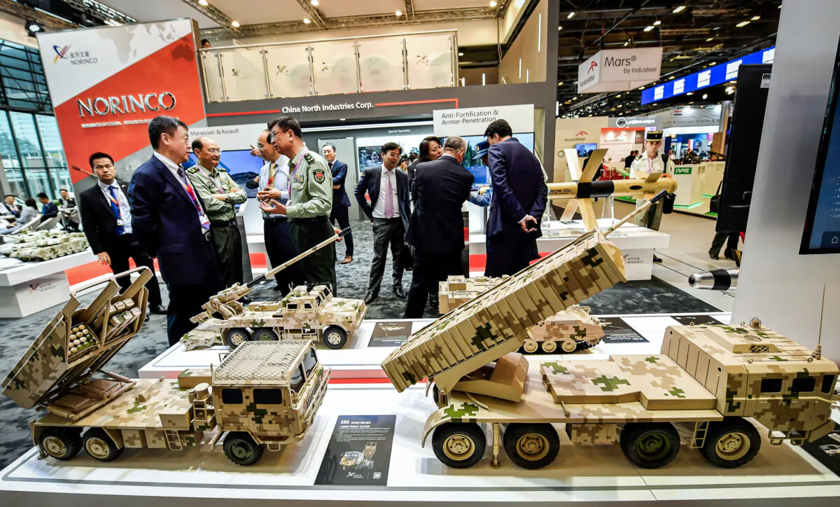 Visitors speak to military personnel next to models of military vehicles manufactured by a Chinese company at an international exhibition in Villepinte, near Paris on June 11, 2018. (Gerard Julien/AFP via Getty Images)