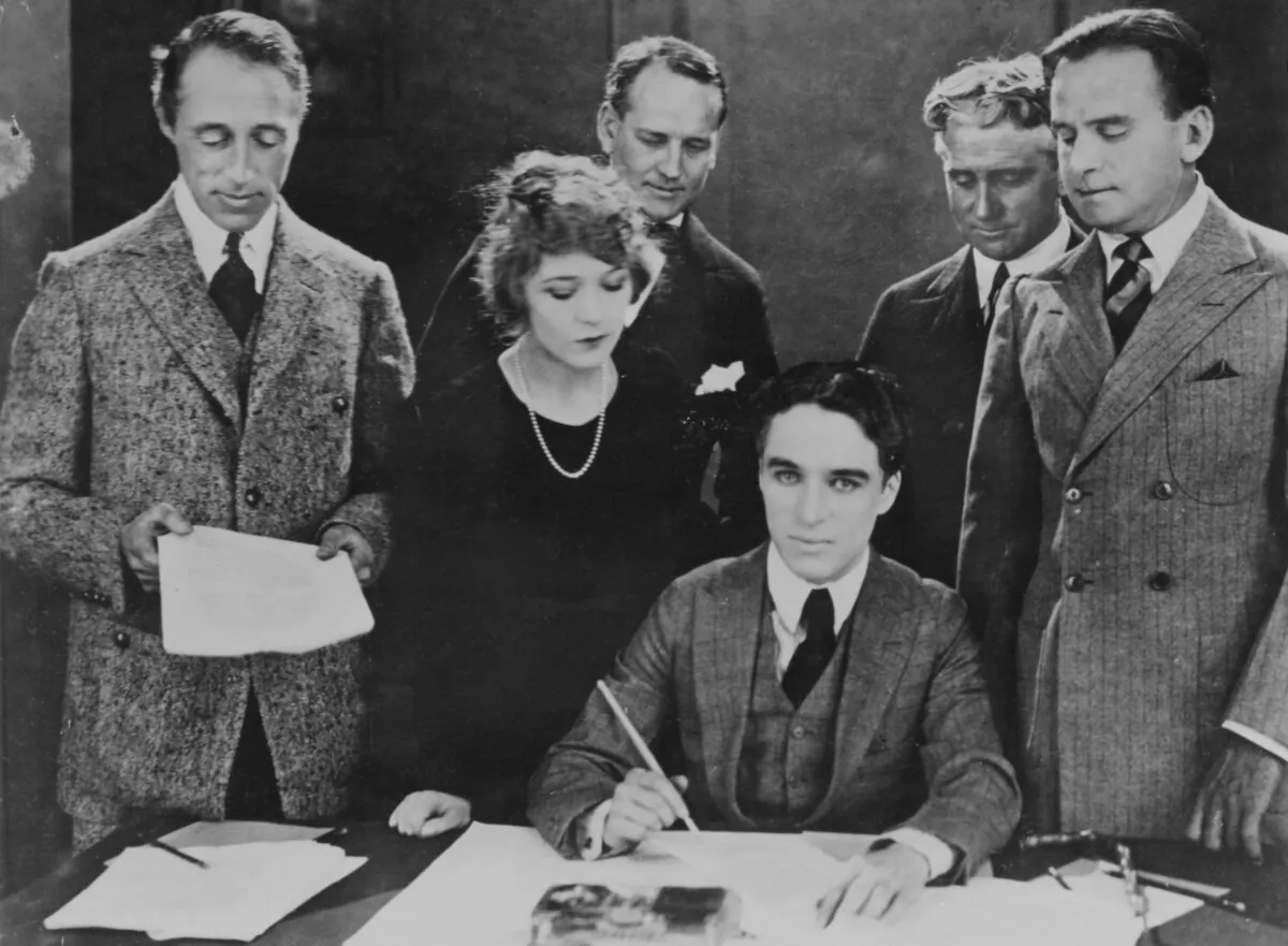 The founders of the new United Artists film studio sign the papers of incorporation, 17th April 1919. From left to right (foreground), they are D. W. Griffith, Mary Pickford, Charlie Chaplin and Douglas Fairbanks, Sr., and behind them are their attorneys Albert Banzhaf and Dennis O'Brien. (Archive Photos/Getty Images)