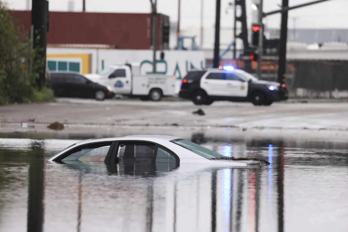 A car sits partially submerged on a flooded road during a rain storm in Long Beach, Calif., on Feb. 1, 2024. (David Swanson/AFP via Getty Images)