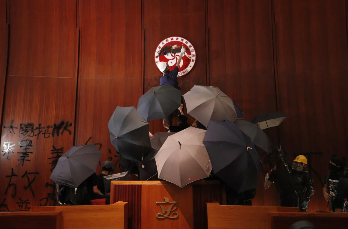 Protesters deface the Hong Kong logo at the Legislative Council to protest against the extradition bill in Hong Kong, on July 1, 2019. (Vincent Yu/AP Photo)