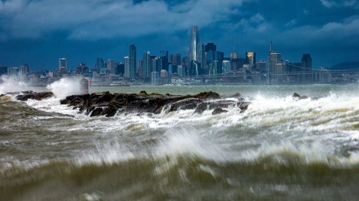 Waves crash over a breakwater in Alameda, Calif., with the San Francisco skyline in the background on Feb. 4, 2024. (Noah Berger/AP Photo)