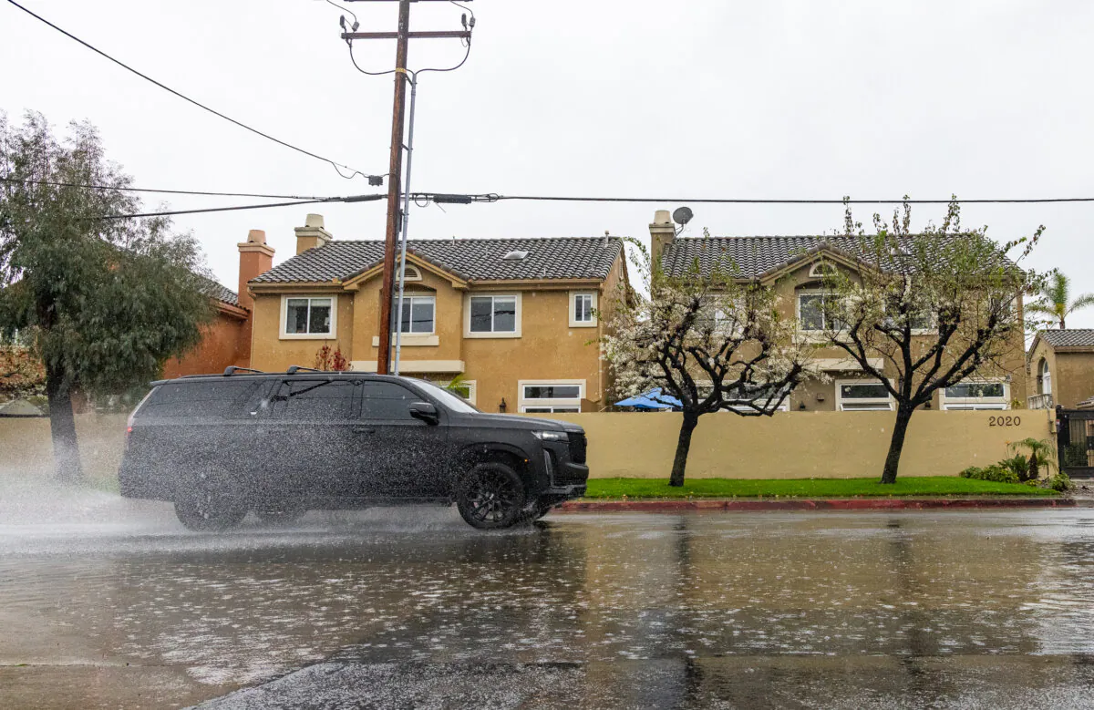Cars drive through flooded streets in Costa Mesa, Calif., on Feb. 5, 2024. (John Fredricks/The Epoch Times)