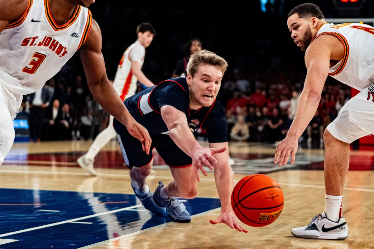 UConn guard Cam Spencer (12) dives for a loose ball as St. John's guards Chris Ledlum (8) and Jordan Dingle (3) reach in during the first half of an NCAA college basketball game in New York on Feb. 3, 2024. (Peter K. Afriyie/AP Photo)