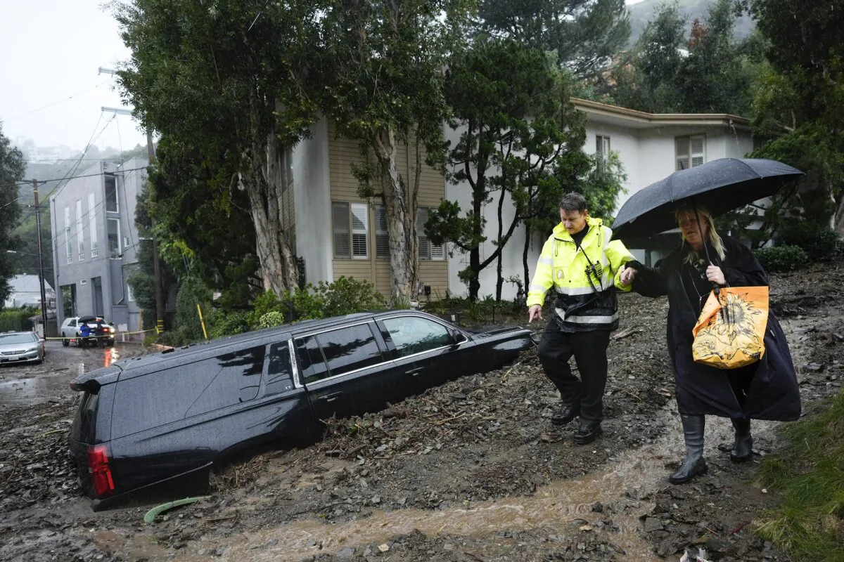 A first responder helps a resident evacuate from a neighborhood after a mudslide in the Beverly Crest area of Los Angeles on Feb. 5, 2024. (Marcio Jose Sanchez/AP Photo)