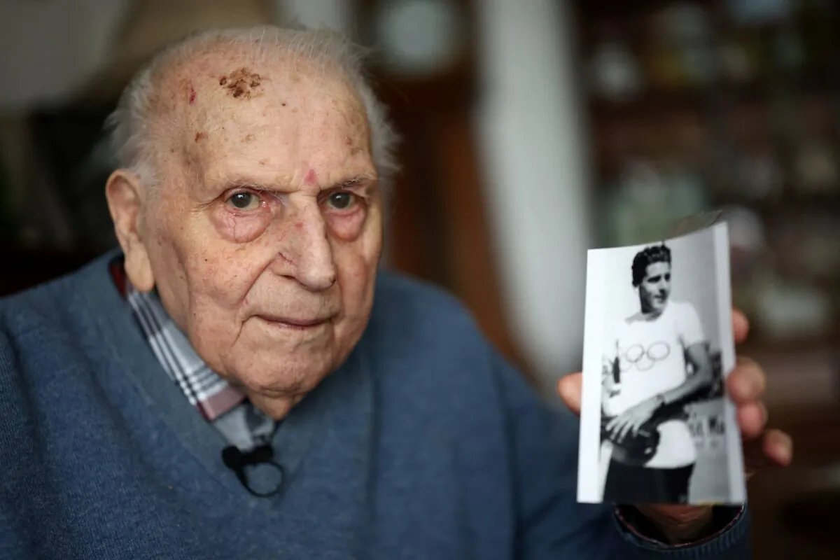 Charles Cost, Olympic champion in Men's Team Pursuit in track cycling at the 1948 London Games and oldest living French Olympic champion, poses with a photo of himself wearing the Olympic jersey, dating from 1948, during an interview at his apartment in Bois-Colombes, near Paris, on Feb. 5, 2024. (Stephanie Lecocq/Reuters)