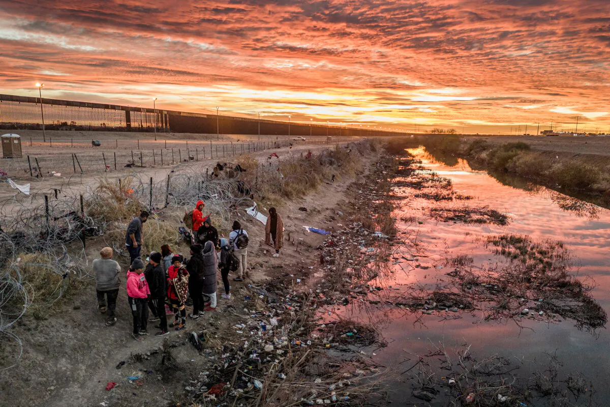Illegal immigrants wait next to razor wire after crossing the Rio Grande into El Paso, Texas, on Feb. 1, 2024. (John Moore/Getty Images)