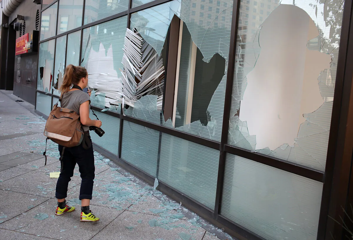 A woman looks through a broken window into an office at the Clorox building in Oakland, Calif., in a file photo. (Justin Sullivan/Getty Images)
