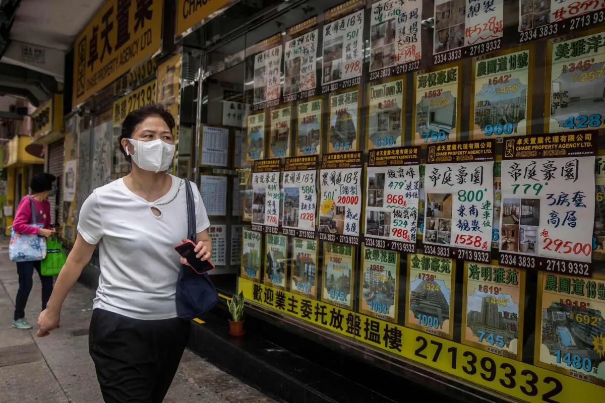 A woman walks past real estate posters in Hong Kong on May 13, 2022,. (Isaac Lawrence/AFP via Getty Images)