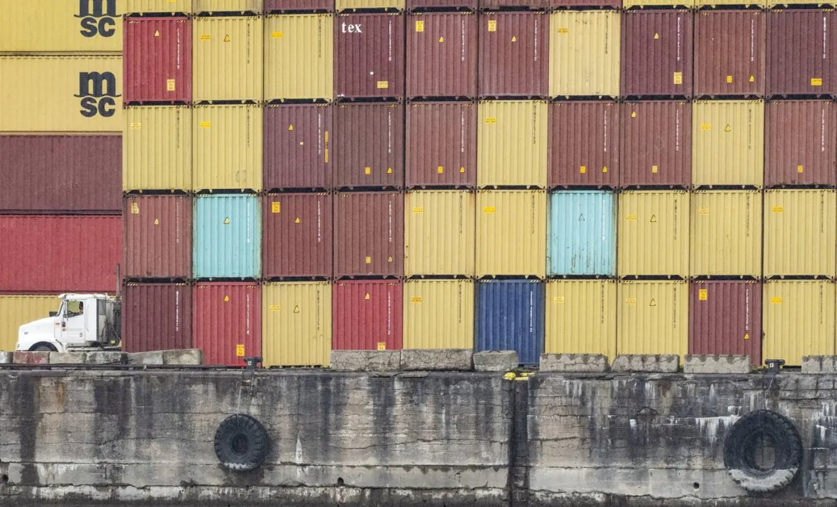 A truck drives past stacked shipping containers in the Port of Montreal on Sept.19, 2023. (The Canadian Press/Christinne Muschi)