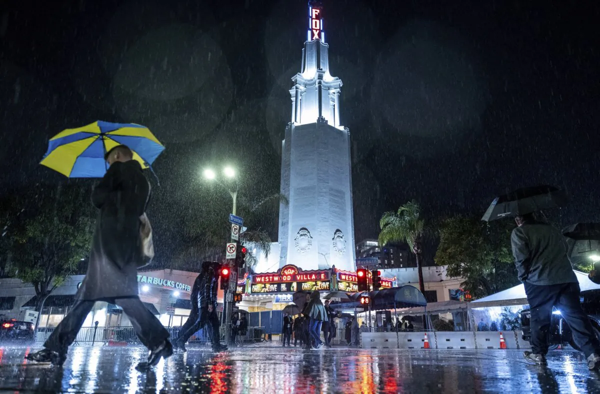 People walk in the rain past the Fox Theater before the premier of Bob Marley: One Love in the Westwood area of Los Angeles on Feb. 6, 2024. (Ethan Swope/AP Photo)