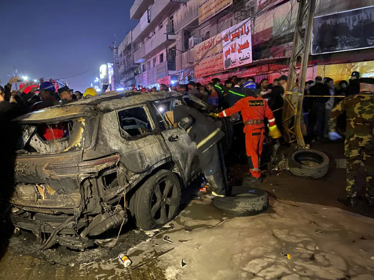 Civil defense members gather at the site of a burned vehicle targeted by a U.S. drone strike in east Baghdad, Iraq, on Feb. 7, 2024. (Hadi Mizban/AP Photo)
