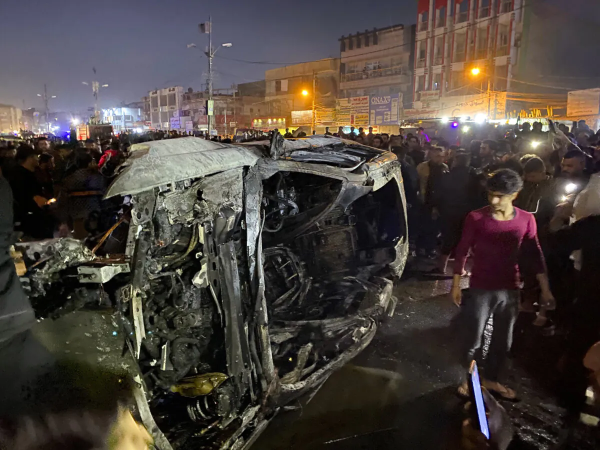 Iraqis gather at the site of a burned vehicle targeted by a U.S. drone strike in east Baghdad, Iraq, Wednesday, Feb. 7, 2024. (AP Photo/Hadi Mizban)