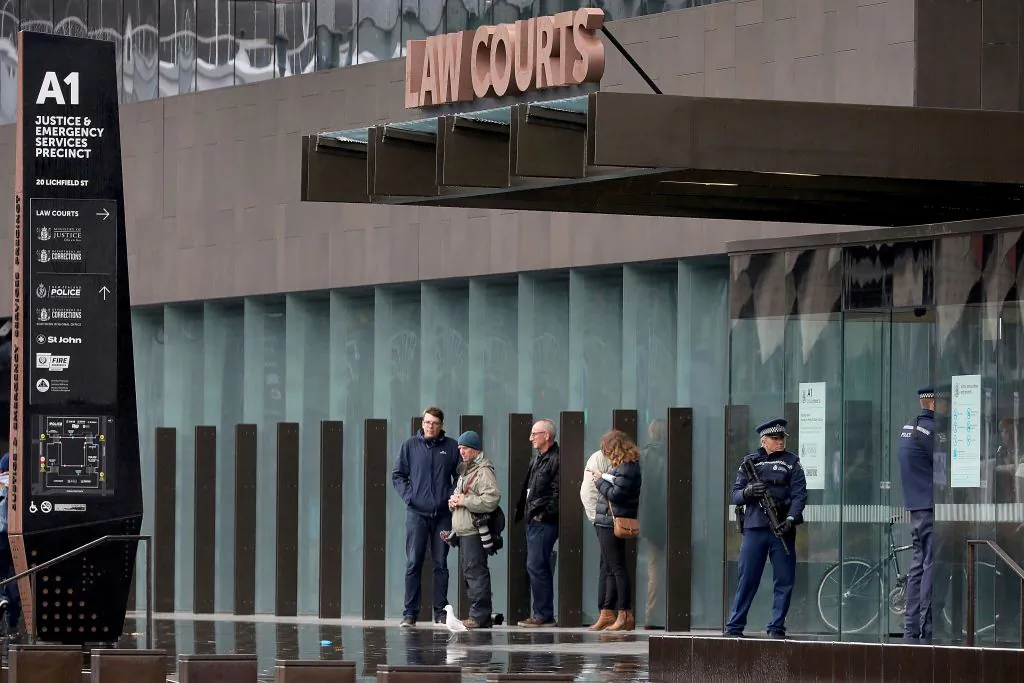 Journalists (C) wait as armed police officers (R) stand guard outside the Christchurch District Court in Christchurch on April 5, 2019. (SANKA VIDANAGAMA/AFP via Getty Images)