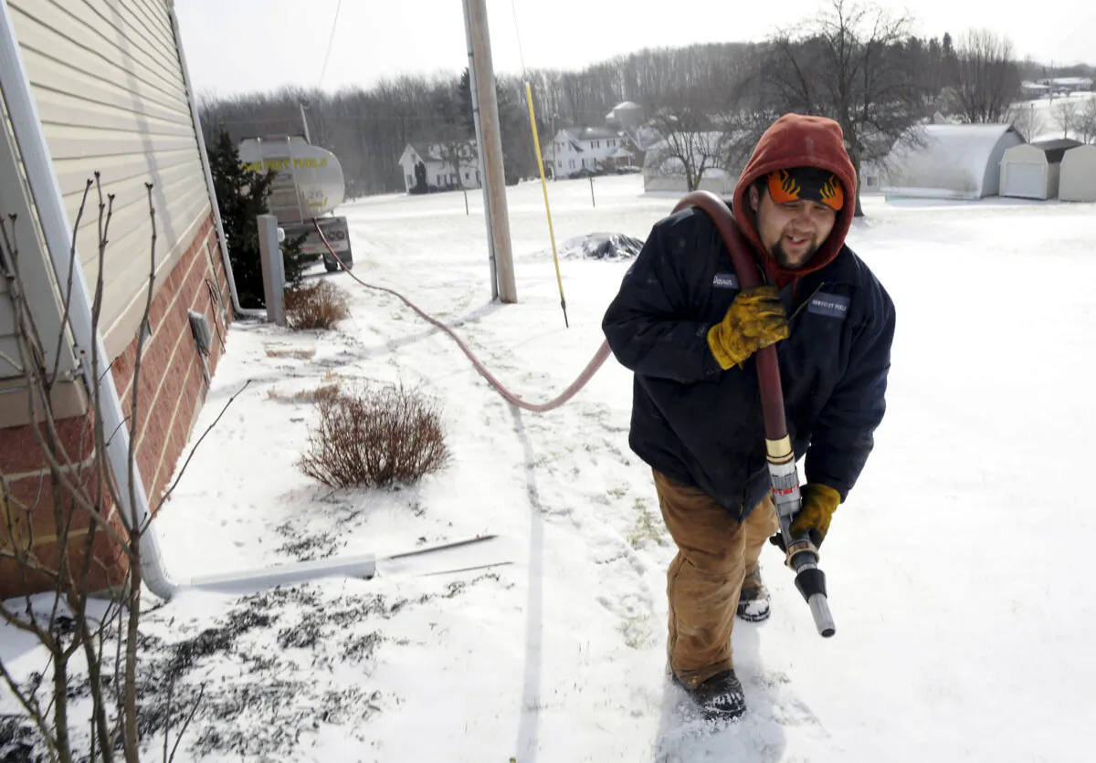 FILE - In this Jan. 7, 2014 file photo, Denver Walker, of Somerset Fuels, makes a heating oil delivery to a home in Jenner Crossroads, Pa. The Energy Department’s annual prediction of winter heating costs released Tuesday, Oct. 7, 2014 says that Americans will pay less because they won’t have to crank up the heat as much. (AP Photo/Tribune-Democrat, John Rucosky, File) MANDATORY CREDIT