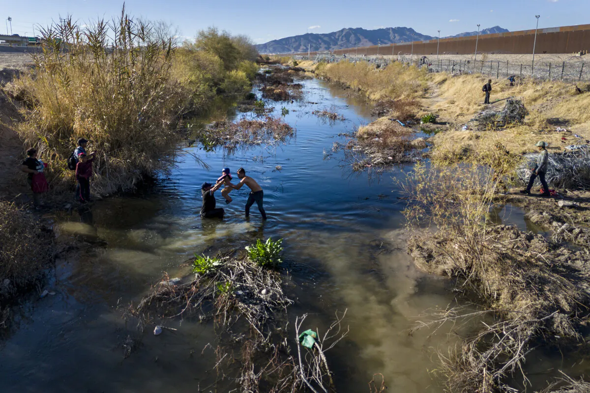 Seen from an aerial view, a child is passed across the Rio Grande while immigrant families cross the U.S.-Mexico border into El Paso, Texas, on Jan. 31, 2024, from Ciudad Juarez, Mexico. (John Moore/Getty Images)