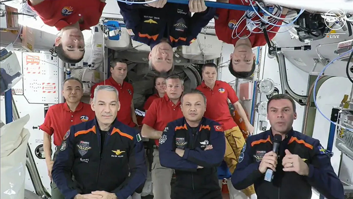 In this image from video, the 11 International Space Station crew members representing Expedition 70 (red shirts) and Axiom Space 3 (dark blue suits) crews gather for a farewell ceremony calling down to mission controllers on Earth on Feb. 2, 2024. (NASA via AP)