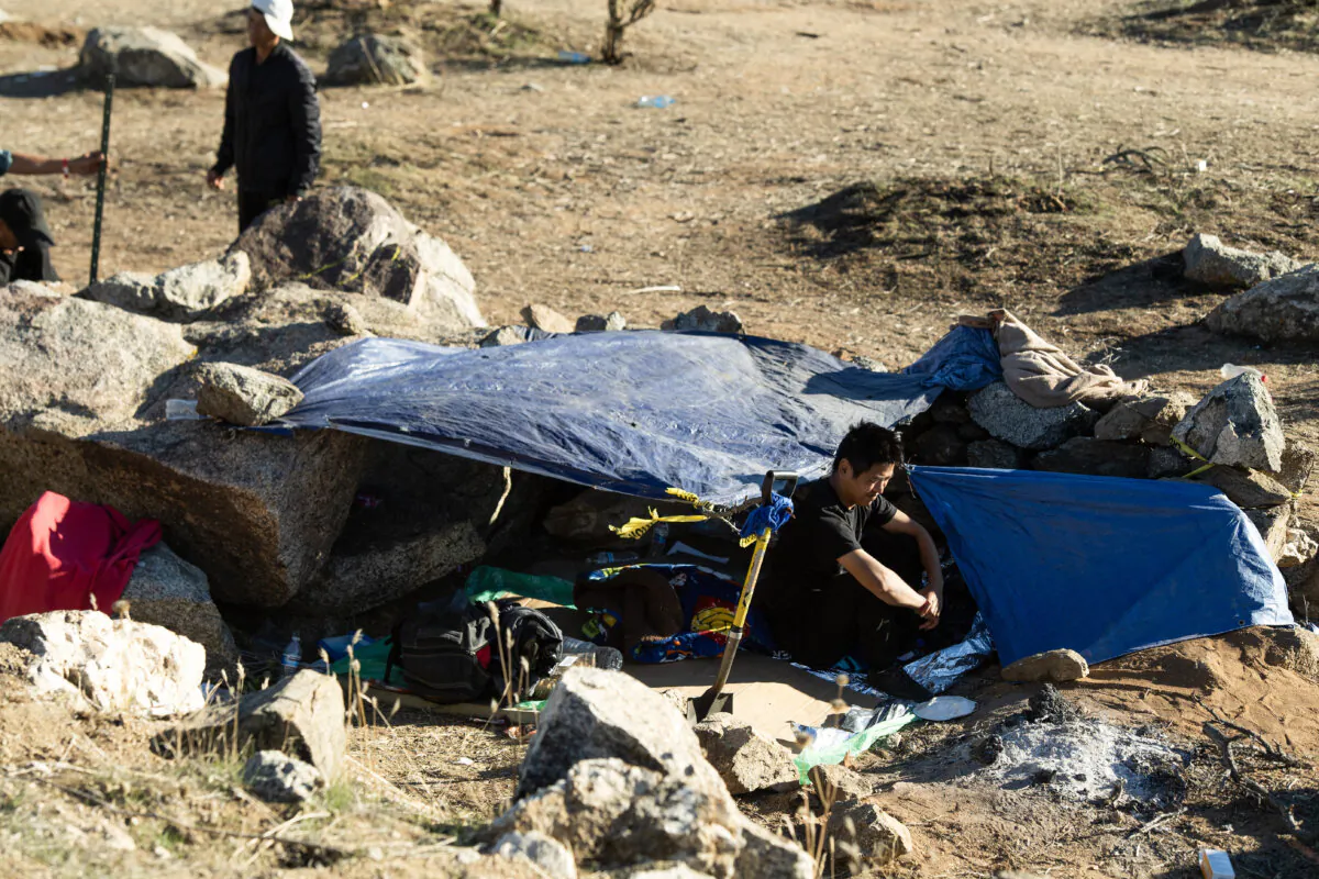 A Chinese migrant sits in front of his tent in a migrant camp on the U.S. side of the border wall separating Mexico from the United States in Jacumba, Calif., on Dec. 6, 2023. (Valerie Macon/AFP via Getty Images)