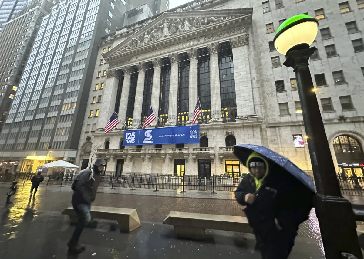 Pedestrians pass the New York Stock Exchange as snow falls, on Feb. 13, 2024. (Peter Morgan/AP Photo)