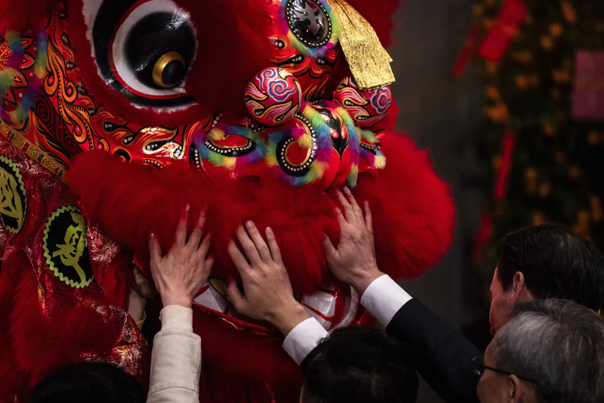 Guests touch a lion dance costume during a ceremony to mark the first trading day of the Year of the Dragon at the Hong Kong Exchanges (HKEX) in Hong Kong, on Feb. 14, 2024. (Louise Delmotte/AP Photo)