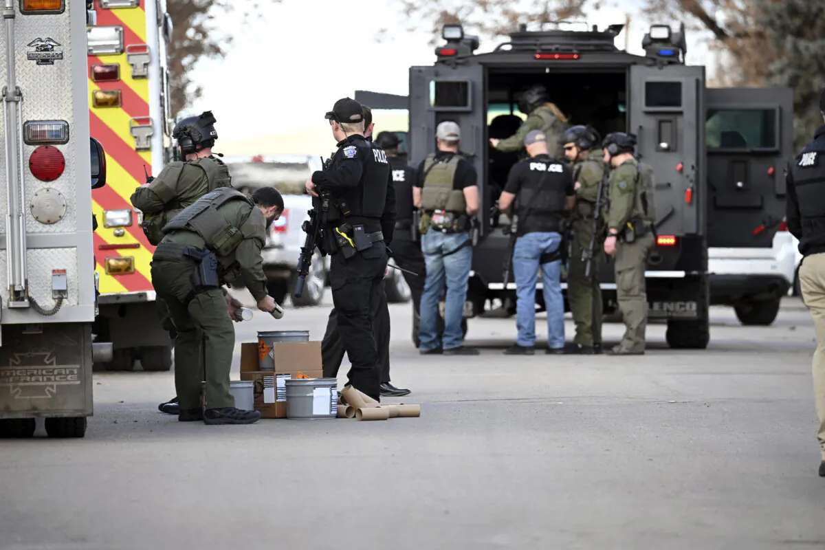 A police officer handles tear gas canisters during a standoff following the fatal shooting of an officer who was serving a trespass warning, in Sheridan, Wyo., on Feb. 13, 2024. (Clint Wood/Sheridan Press via AP)