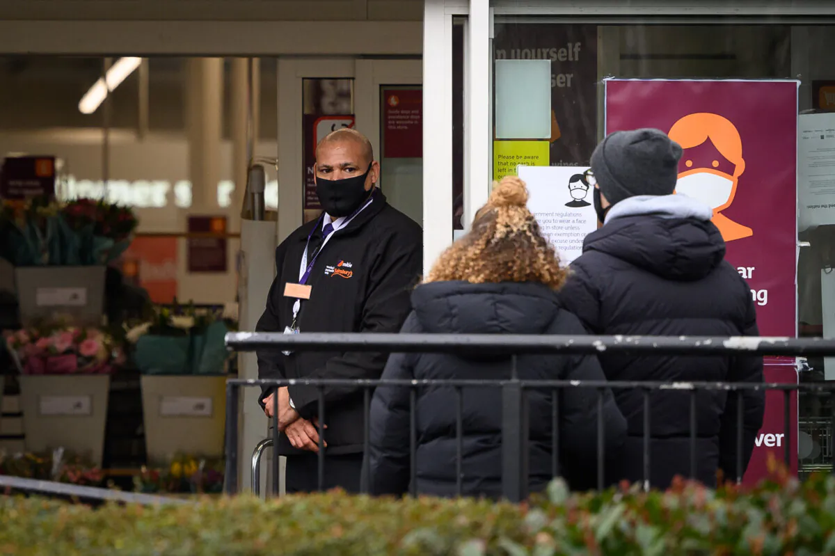 A security guard (L) stands at the entrance to a branch of Sainsbury's in London on Jan. 12, 2021. (Leon Neal/Getty Images)