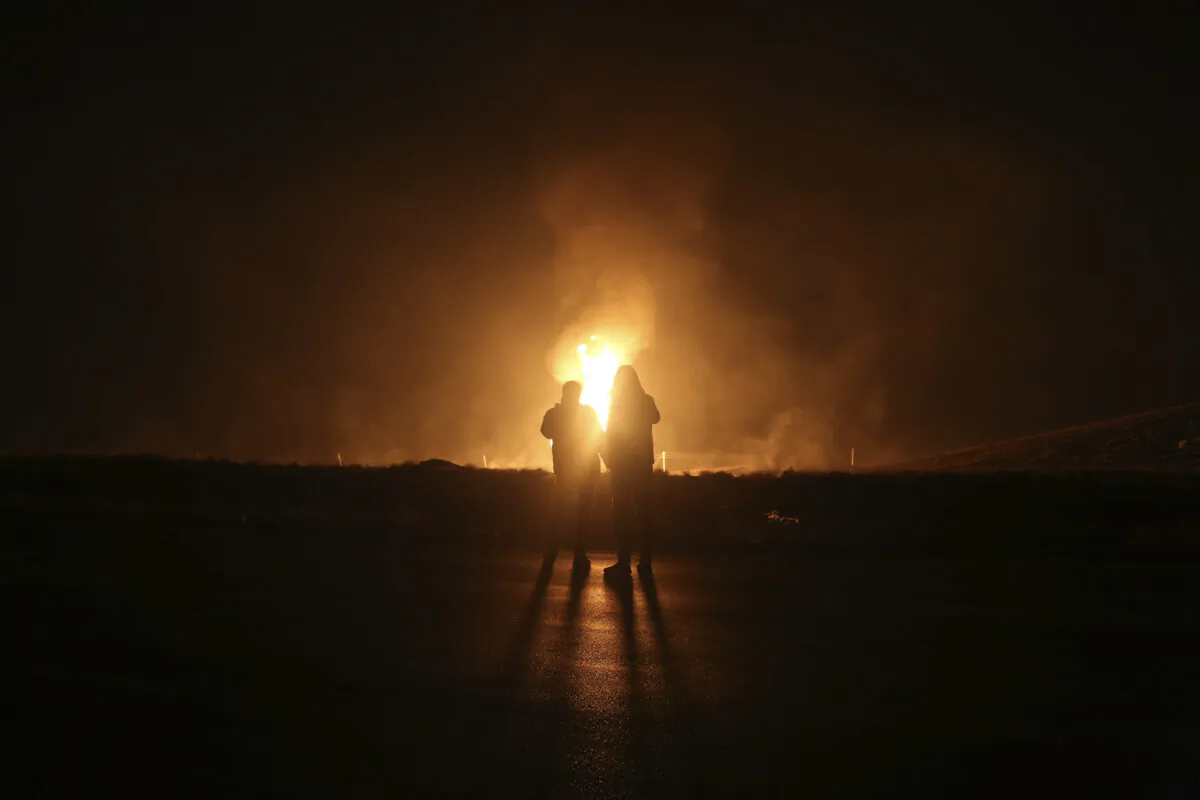 Two men look at flames after a natural gas pipeline explodes outside the city of Boroujen in the western Chaharmahal and Bakhtiari Province, Iran, on Feb. 14, 2024. (Reza Kamali Dehkordi/Fars News Agency via AP)